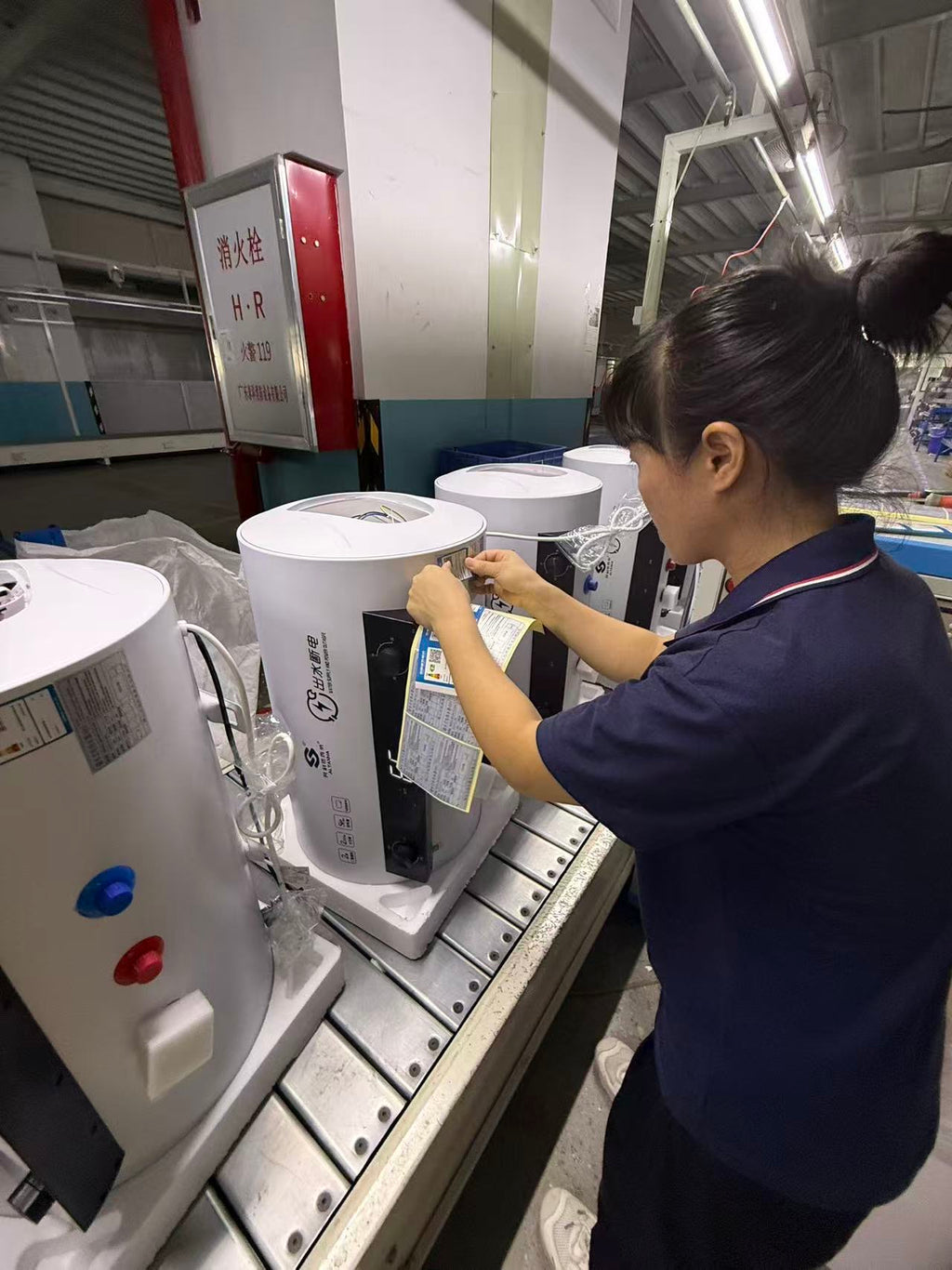Worker completing manual wiring during water heater assembly