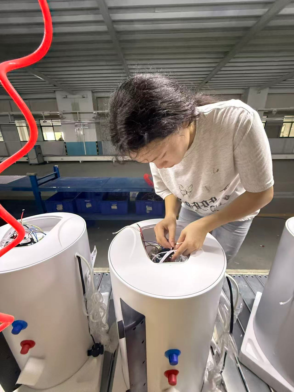 Worker applying product labels during final water heater assembly